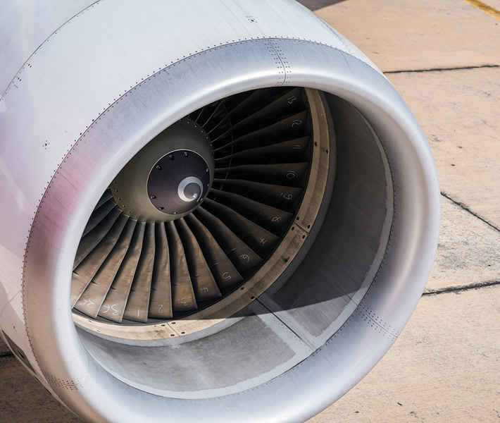 Aircraft engine close-up showing turbine blades and nacelle.